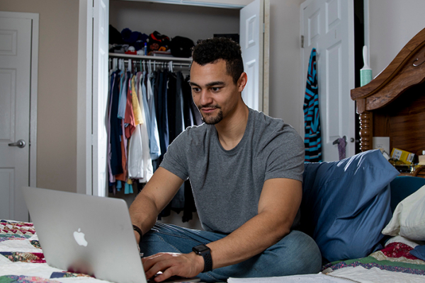 student sitting on bed working